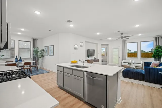 a large kitchen with stainless steel appliances a stove a sink a dining table and chairs