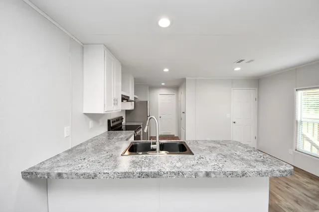 a kitchen with kitchen island granite countertop a sink a counter top space and cabinets