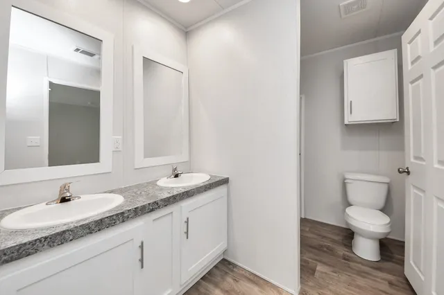 a bathroom with a granite countertop sink a toilet and a mirror