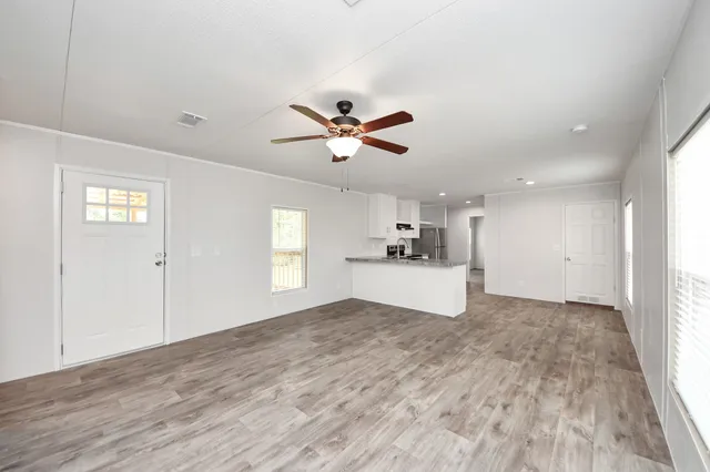 a view of empty room with wooden floor and ceiling fan