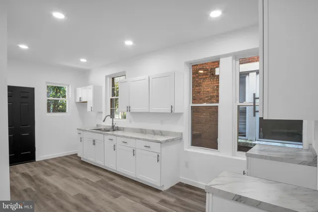 a view of a hallway with wooden floor and a bathroom