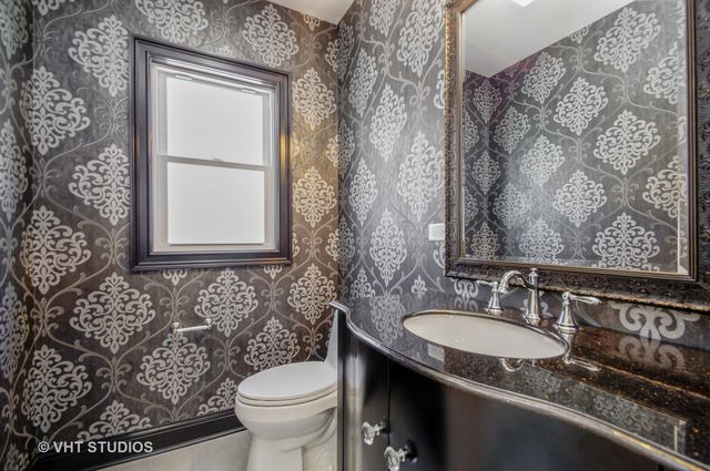 a bathroom with a granite countertop sink and a toilet