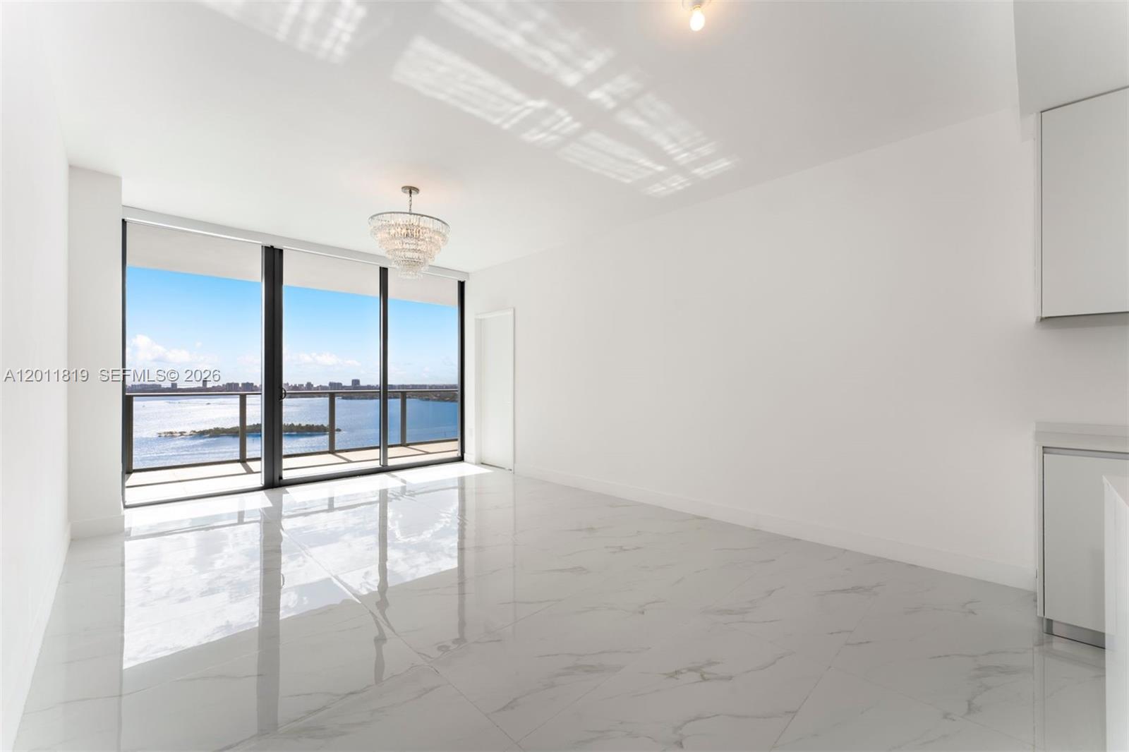 700 Northeast 24th Street, Unit 2504 Miami, FL 33137 - Photo 19 of 52 Serene primary suite offering unobstructed water views, direct terrace access, oversized walk-in closets, and floor-to-ceiling windows for a true 'mansion in the sky' feel.