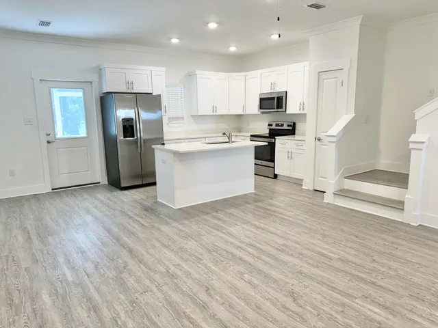 a large kitchen with stainless steel appliances kitchen island a large counter top and wooden floors