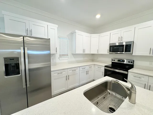 a kitchen with white cabinets and black appliances