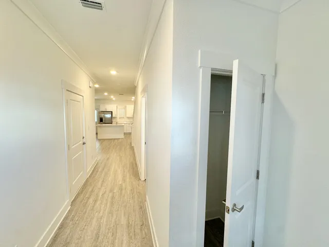 a view of a hallway with wooden floor and a bathroom