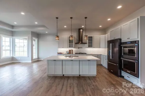 a large kitchen with stainless steel appliances a large counter top a sink a refrigerator and a window
