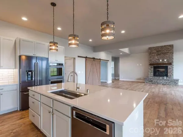 a kitchen with stainless steel appliances granite countertop a sink a refrigerator and a stove top oven