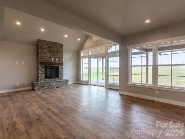 an empty room with wooden floor and a fireplace