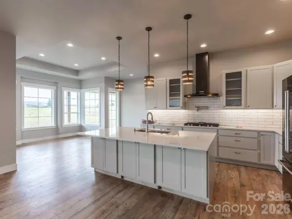 a large kitchen with granite countertop a stove a sink a center island and wooden floor