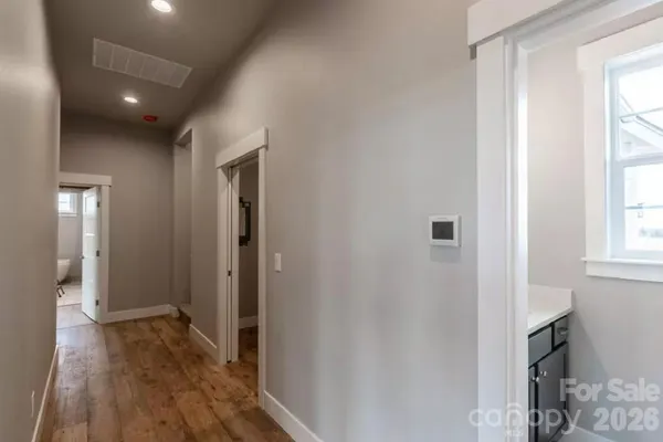 a view of hallway with window and wooden floor