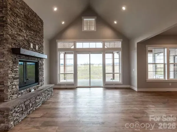 a view of an empty room with wooden floor and a fireplace