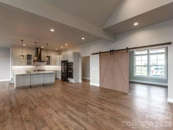 a view of a kitchen with kitchen island a sink wooden floor and a refrigerator