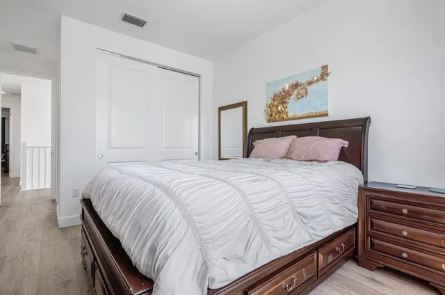 a bedroom with a bed and a dresser with wooden floor