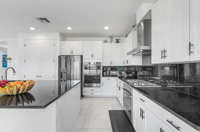 a kitchen with granite countertop a refrigerator and a stove top oven