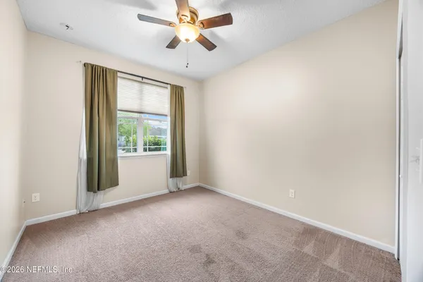 an empty room with windows and fan