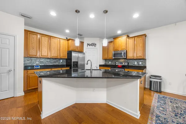 a kitchen with stainless steel appliances granite countertop a sink a stove top oven a counter space and cabinets