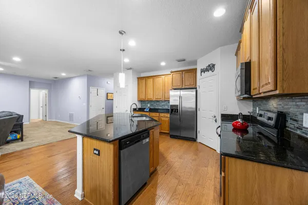 a kitchen with stainless steel appliances granite countertop a sink refrigerator and cabinets