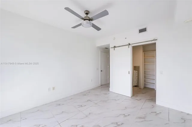 an empty room with closet and a ceiling fan