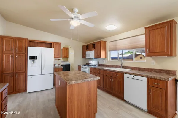 a kitchen with stainless steel appliances granite countertop a refrigerator a sink dishwasher a stove with white cabinets and wooden floor