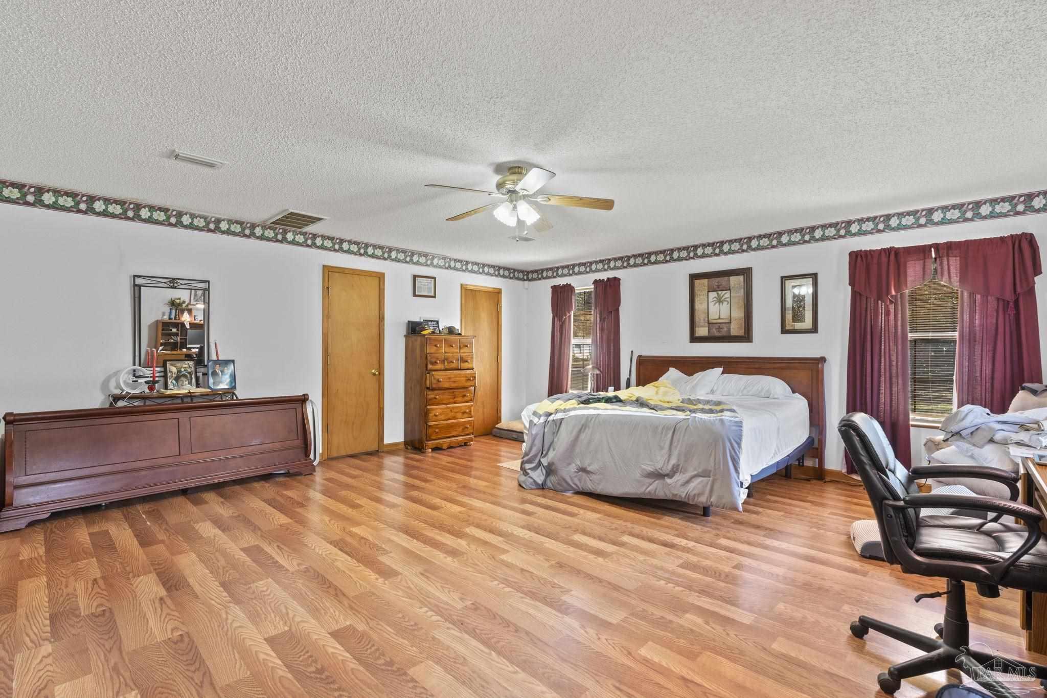 3319 Bob Tolbert Road Navarre, FL 32566 - Photo 17 of 51 a spacious bedroom with a large bed and a chandelier