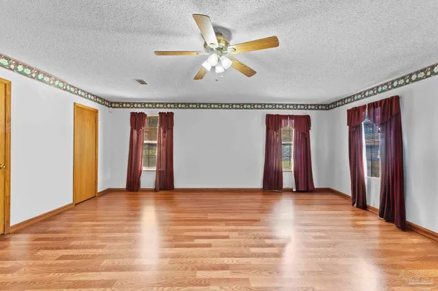 a view of an empty room with window and wooden floor