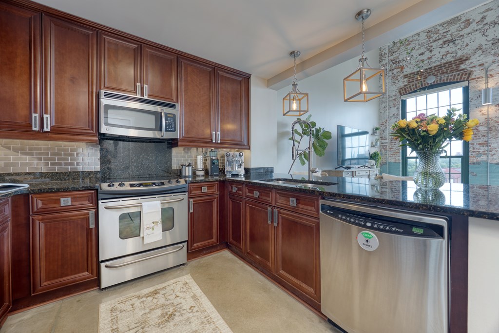 1201 Front Avenue, Unit 522 Columbus, GA 31901 - Photo 8 of 56 a kitchen with granite countertop wooden cabinets stainless steel appliances and a potted plant