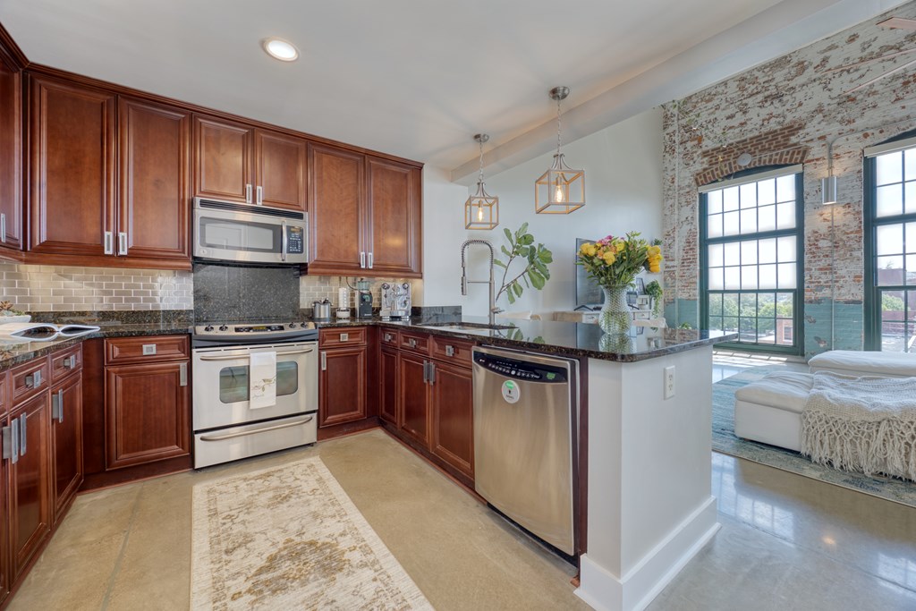 1201 Front Avenue, Unit 522 Columbus, GA 31901 - Photo 10 of 56 a kitchen with stainless steel appliances granite countertop a stove a sink and a microwave