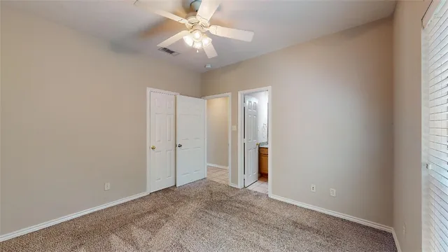 an empty room with chandelier fan and windows