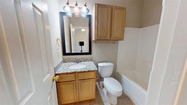 a bathroom with a granite countertop toilet sink and mirror