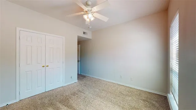 an empty room with a ceiling fan and a window