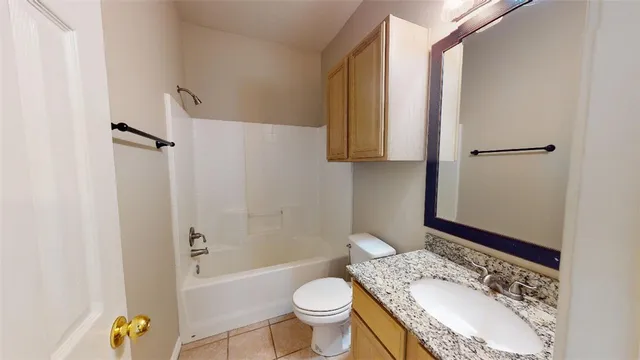 a bathroom with a granite countertop toilet sink and mirror