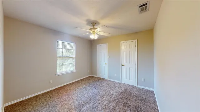 an empty room with windows and ceiling fan