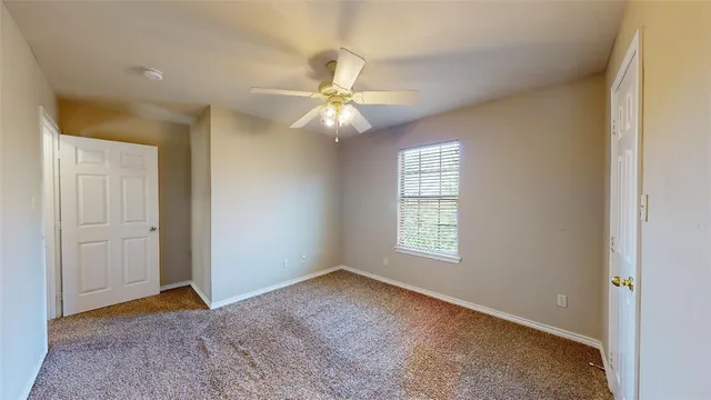 an empty room with windows and fan