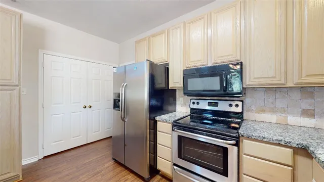 a kitchen with granite countertop a stove microwave and refrigerator
