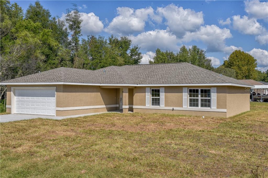 2304 Southwest 168th Loop Ocala, FL 34473 - Photo 1 of 1 a front view of house with yard and trees in the background