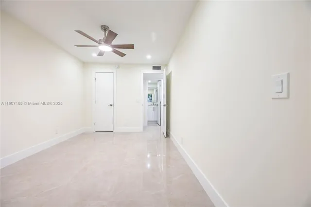 an empty room with windows and fan