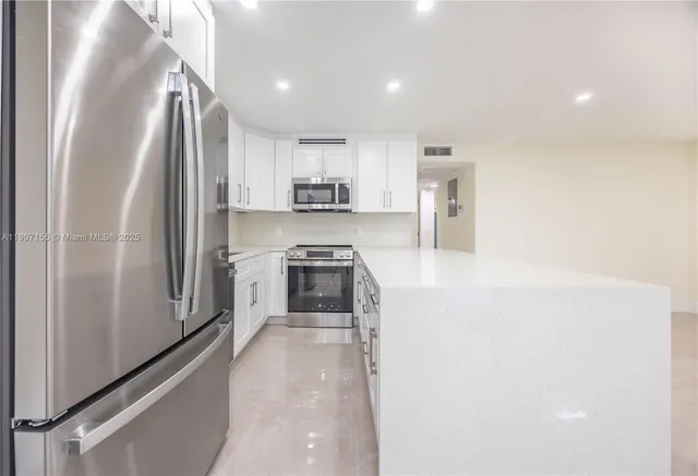 a kitchen with stainless steel appliances granite countertop a refrigerator a stove and a sink