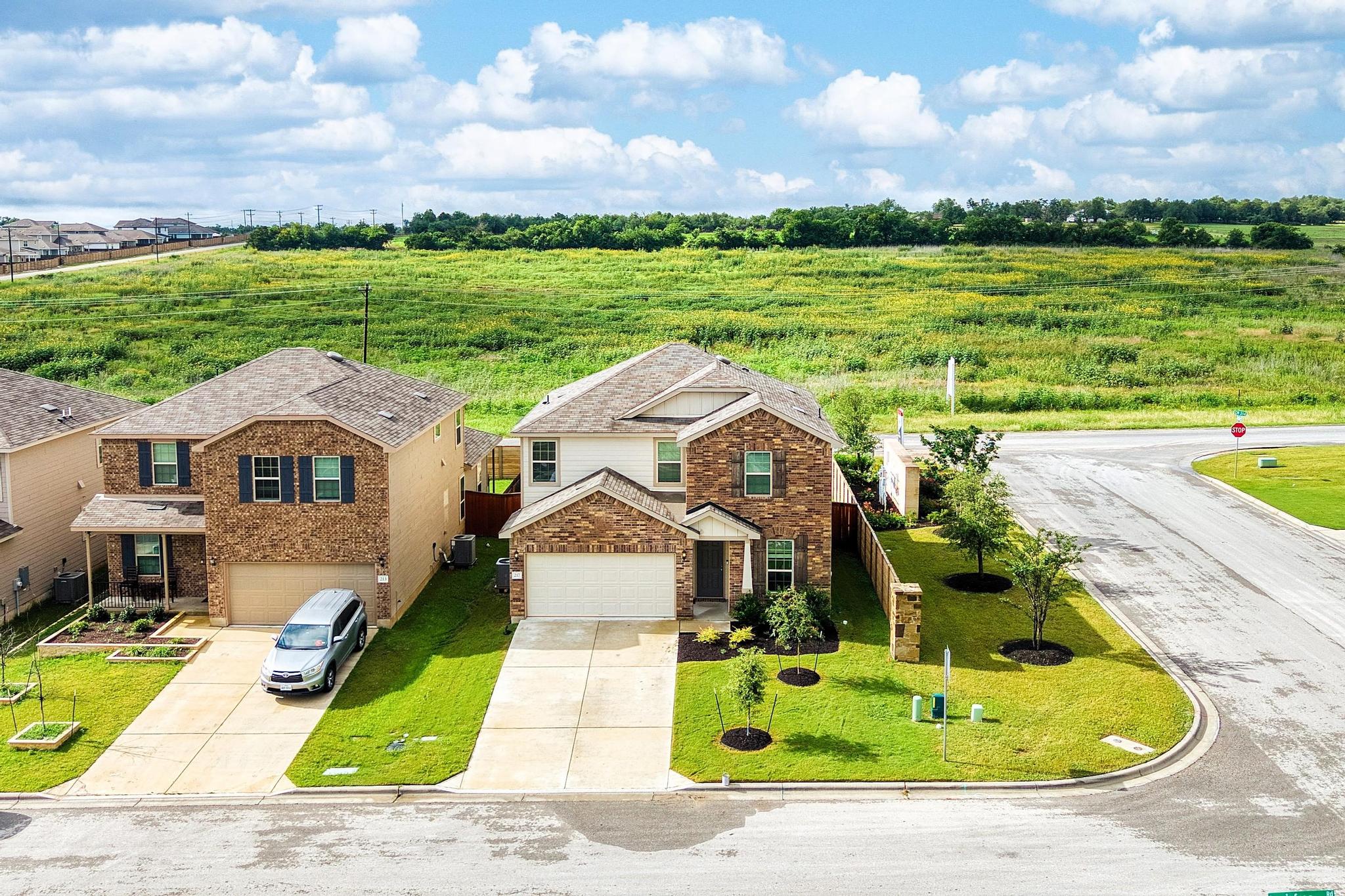 217 Innisfree Road Jarrell, TX 76537 - Photo 3 of 39 A classic brick exterior graces this appealing two-story home, nestled on a corner lot with a green landscape.