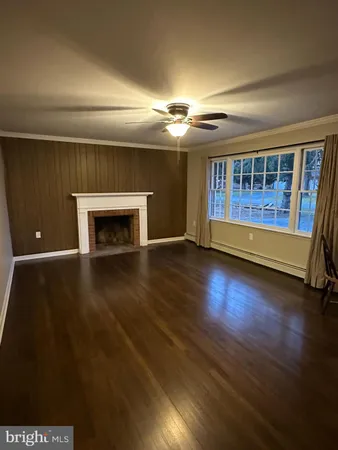 an empty room with wooden floor fireplace and windows