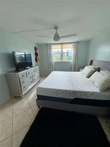 a bedroom with a bed and a flat tv screen on dresser