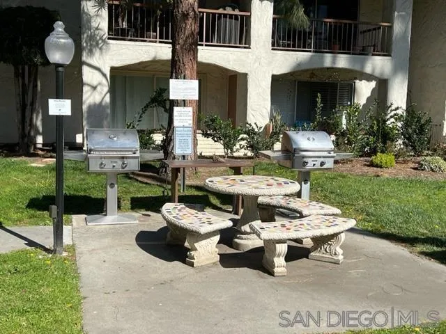 5989 Rancho Mission Road, Unit 201 San Diego, CA 92108 - Photo 13 of 14 a view of a patio with table and chairs potted plants and palm trees