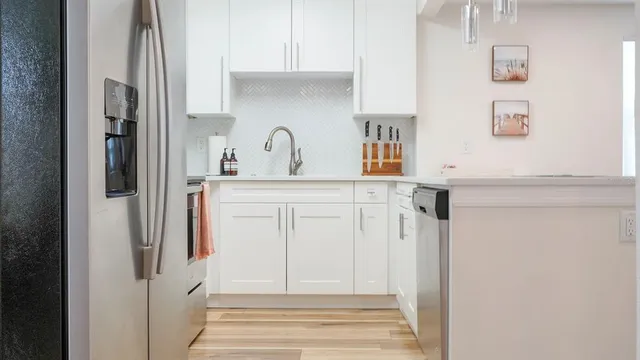 a kitchen with stainless steel appliances granite countertop a stove a refrigerator a oven a white table and chairs with wooden floor