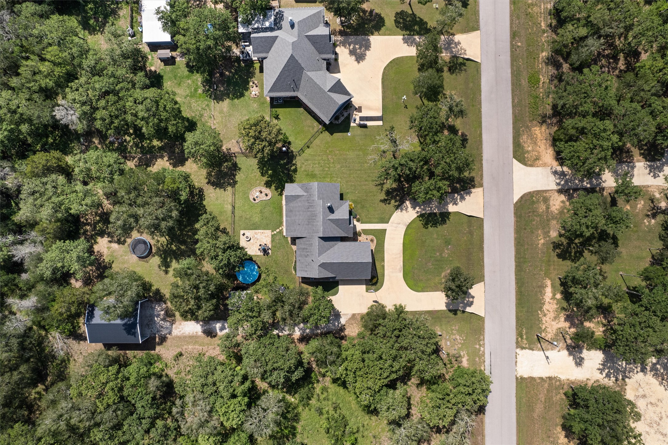 136 Fawn Hollow Elgin, TX 78621 - Photo 40 of 40 Aerial perspective showcasing a residential property with a dark shingle roof, accompanied by a detached structure with a dark shingle roof