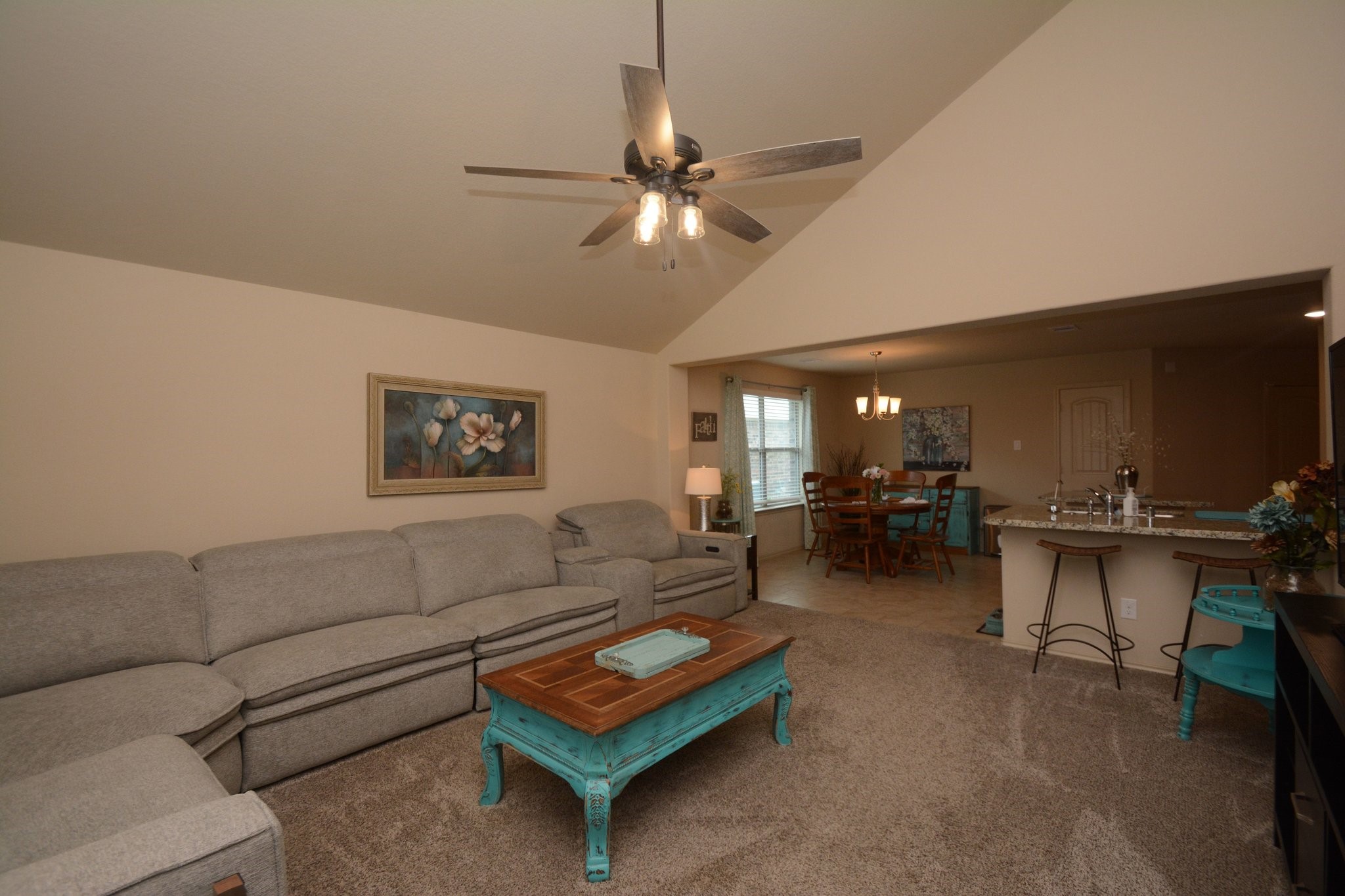 23318 Dukes Run Drive Spring, TX 77373 - Photo 15 of 41 This cozy living space features a vaulted ceiling with a modern ceiling fan. It opens to a dining area and a kitchen bar with seating, creating a welcoming and connected atmosphere.