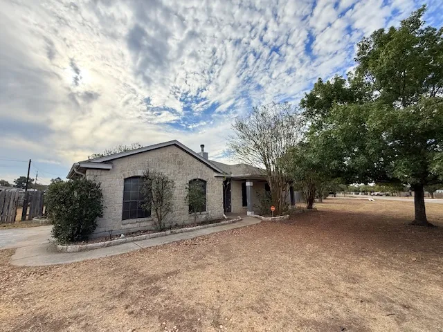 a view of a house with a yard and large tree