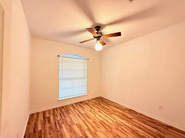 an empty room with a window and ceiling fan