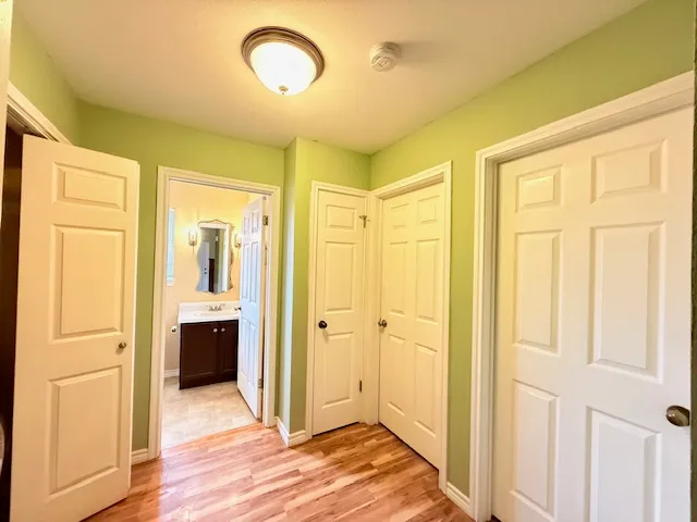 a view of a hallway with wooden floor and cabinet
