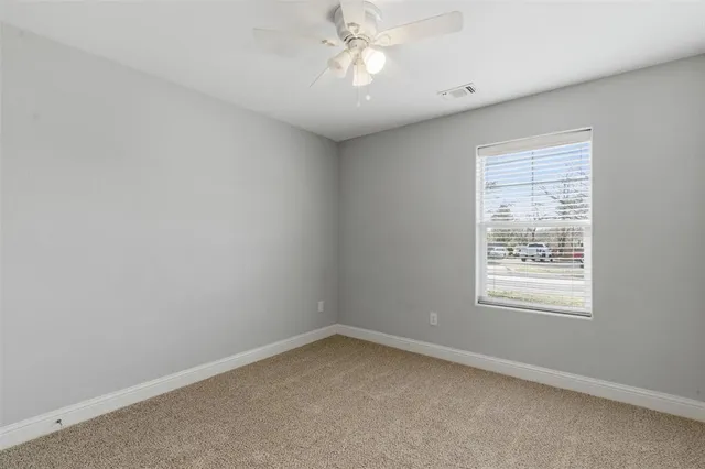 an empty room with a window and a fan