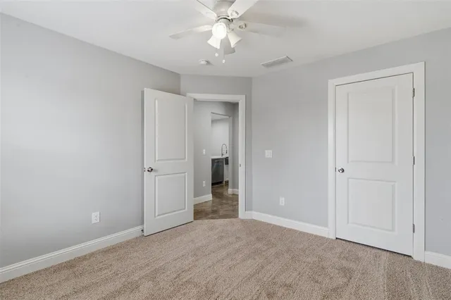 a view of an empty room and chandelier fan